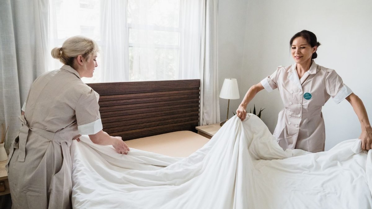 Hotel housekeeping trainees making a bed in a guest room