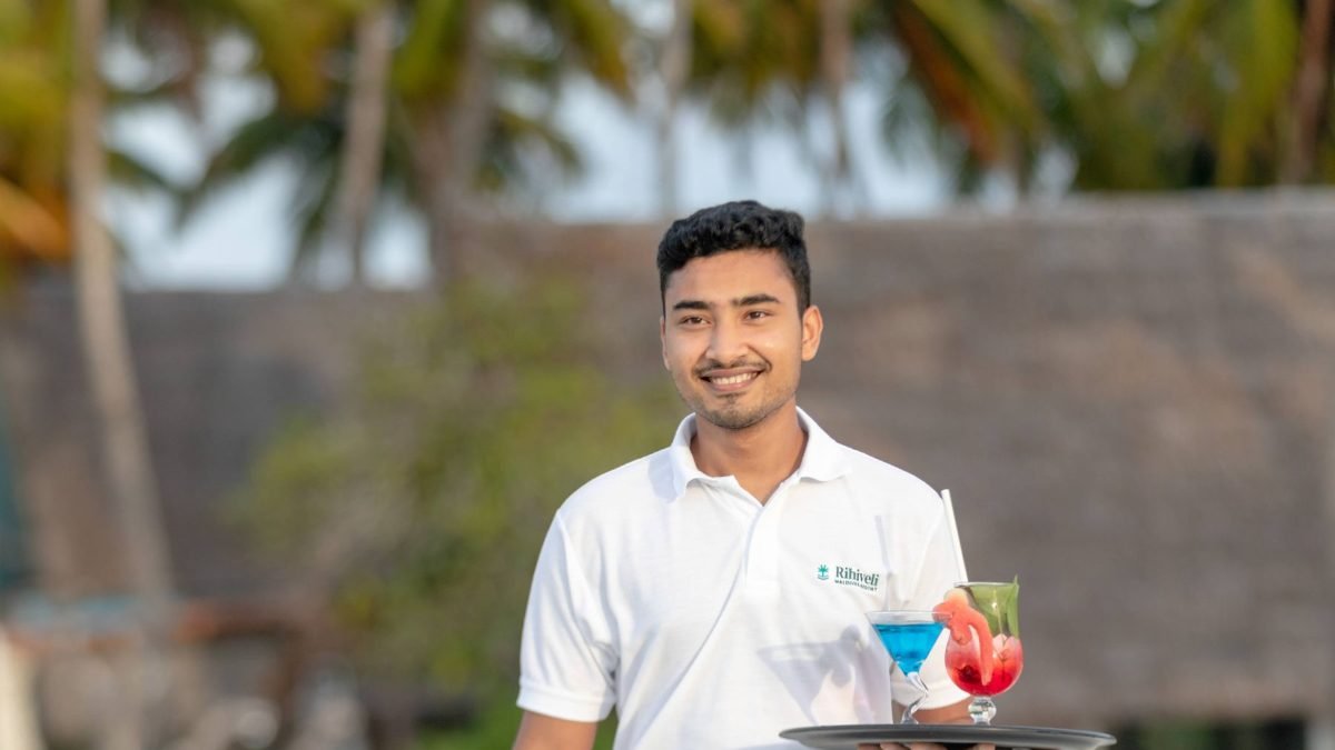 Smiling young hospitality professional serving drinks at a beach resort